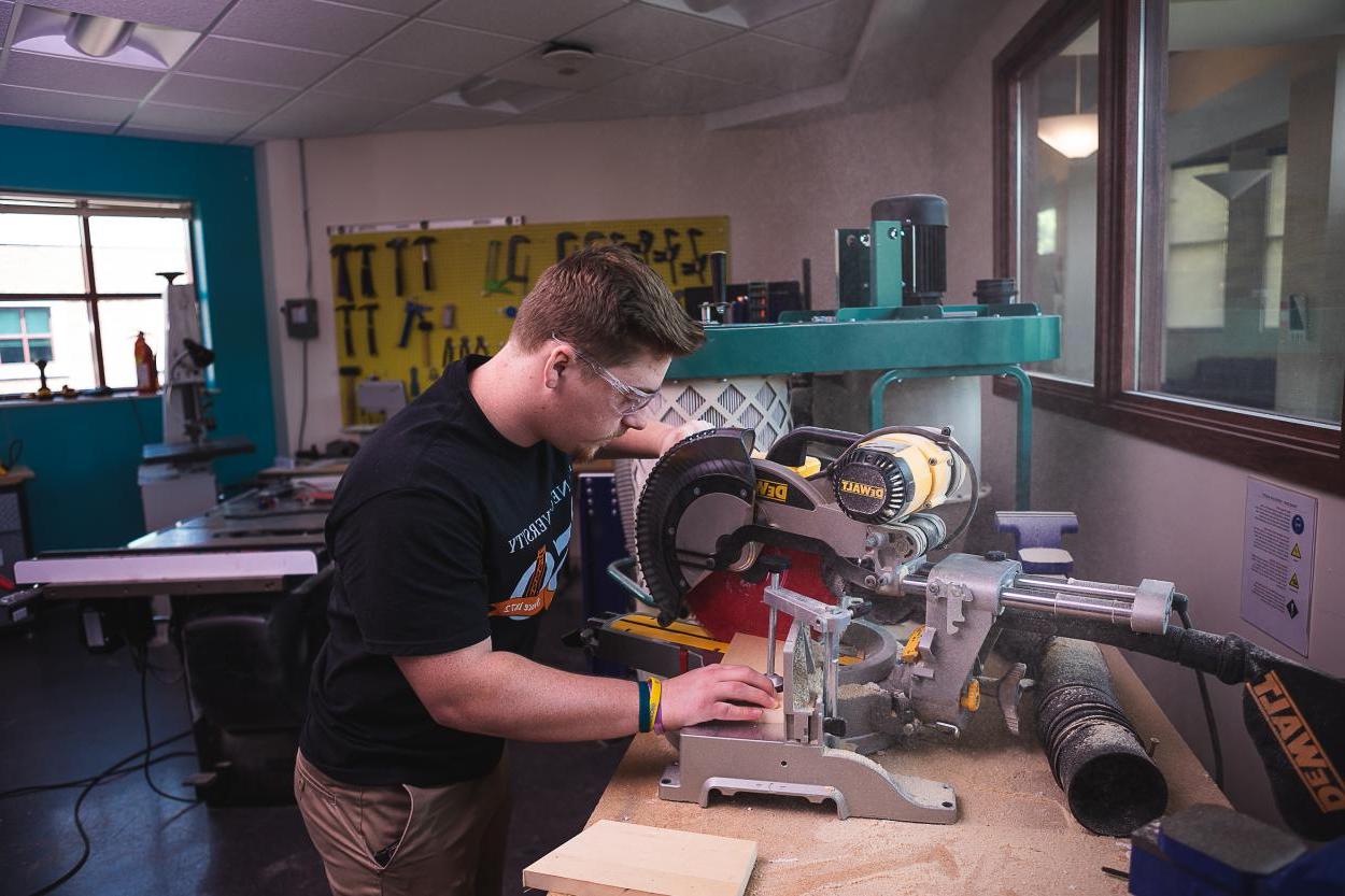 Jeremey Allgeyer '24 uses a circular saw to trim a piece of wood in the engineering and physics department lab.